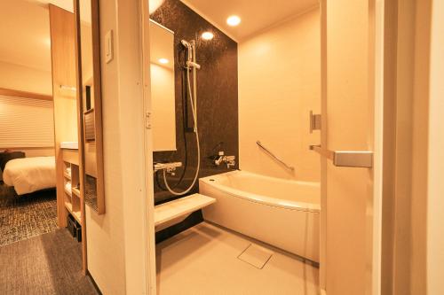 a bathroom with a tub and a toilet and a sink at Richmond Hotel Premier Kyoto Ekimae in Kyoto