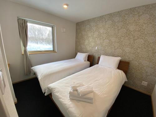 two beds in a hotel room with a window at Yuki Kawa in Niseko