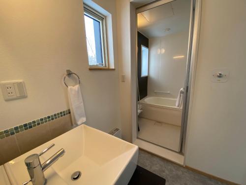 a white bathroom with a sink and a shower at Yuki Kawa in Niseko