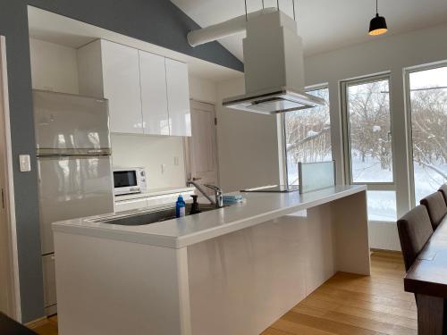 a white kitchen with a sink and a microwave at Yuki Kawa in Niseko