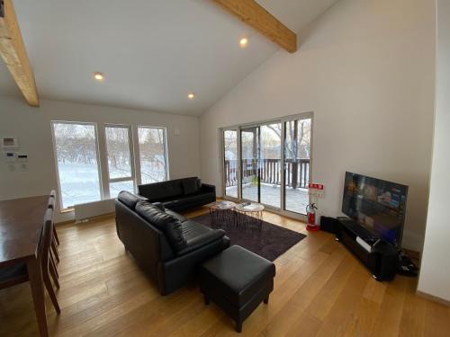 a living room with a black leather couch and a television at Yuki Kawa in Niseko