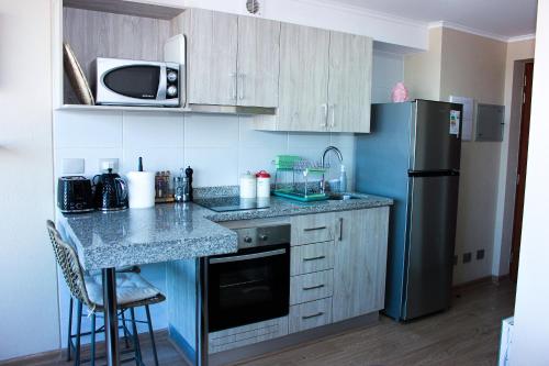 a small kitchen with a counter and a refrigerator at Departamento céntrico Chillán con estacionamiento in Chillán