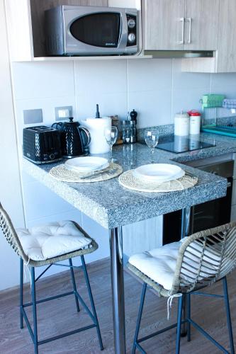 a kitchen counter with two plates and a microwave at Departamento céntrico Chillán con estacionamiento in Chillán
