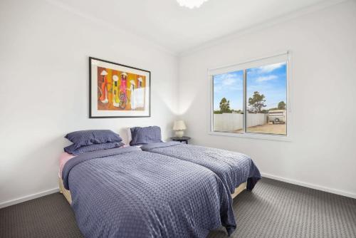 a white bedroom with a bed and a window at The White House in Wellington East