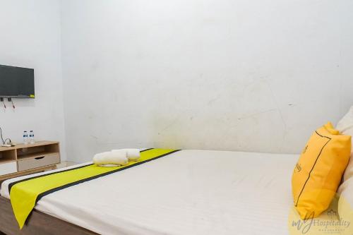 a bedroom with a bed with yellow and white sheets at Anggrek Guest House Cirebon in Tangkil