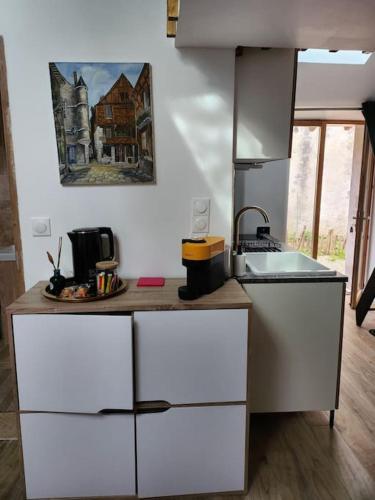 une cuisine avec des armoires blanches et un comptoir dans l'établissement La maison du lavoir, à Ballan-Miré