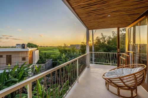 a balcony with a chair and a view of a field at Pagi Villas by Betterplace in Canggu