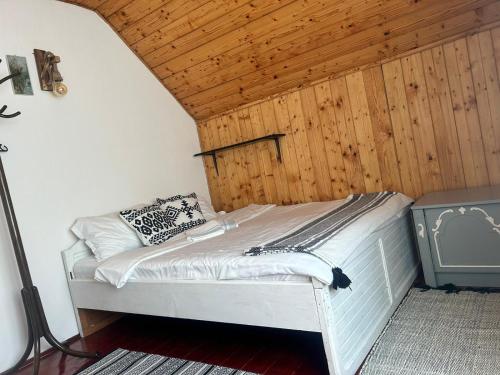 a bed in a room with a wooden ceiling at OLD SHEPHERD Guest House in Râșca
