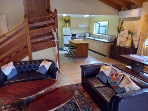 a living room with a couch and a kitchen at Grampians Trail Cottage in Halls Gap