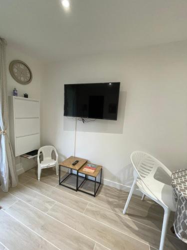 un salon avec une télévision à écran plat au mur dans l'établissement 2p rénové Idéal famille proche de la mer, à Cabourg