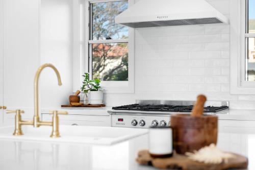 a white kitchen with a sink and a stove at "Casa di Mare=" House by the Sea - Belle Escapes Jervis Bay in Vincentia