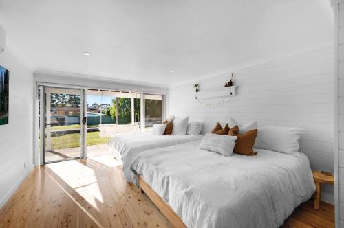 two beds in a room with white walls at "Casa di Mare=" House by the Sea - Belle Escapes Jervis Bay in Vincentia