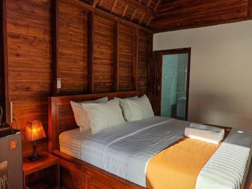 a bedroom with a bed with wooden walls and a window at Aming Villa Balangan in Jimbaran