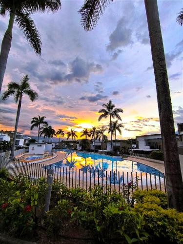 a swimming pool with palm trees and a sunset at Casa Premium Las Palmas San Jeronimo in San Jerónimo