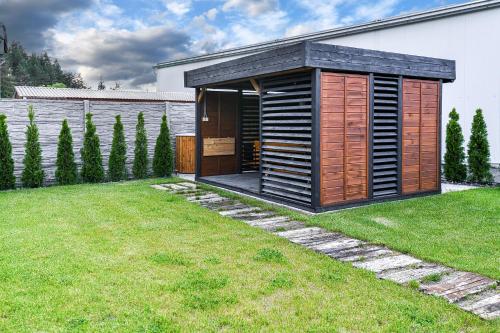 a wooden shed in a yard next to a house at Apartmány K&K in Liptovský Hrádok