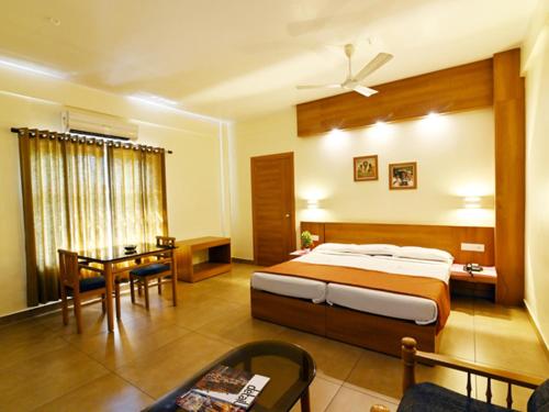 a bedroom with a bed and a table and a desk at Maharani Hotel in Kozhikode