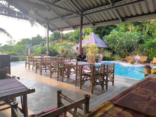 a patio with tables and chairs next to a pool at Sairee View Resort in Koh Tao