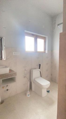 a white bathroom with a toilet and a window at The apricot house in Leh