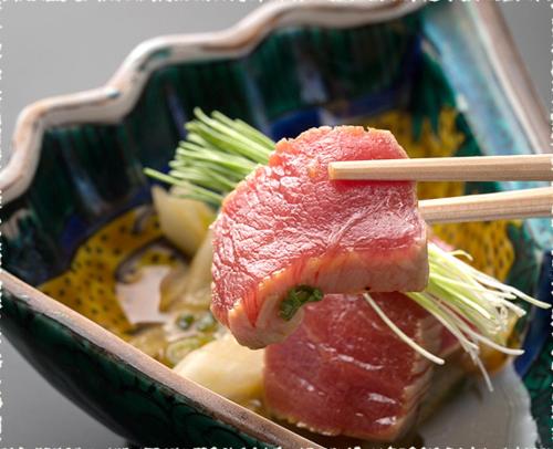 a piece of meat in a container with chopsticks at 金沢湯涌温泉湯の出 in Kanazawa