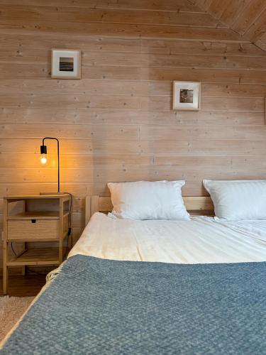 a bedroom with a bed and a wooden wall at Vila Ambasada in Šventoji