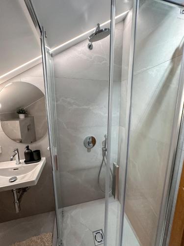 a shower with a glass door next to a sink at Vila Ambasada in Šventoji