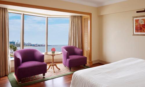 a hotel room with two purple chairs and a window at Ramada Plaza By Wyndham Palm Grove in Mumbai