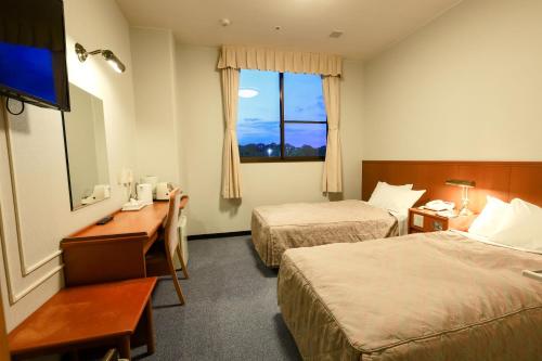 a hotel room with two beds and a desk and a window at Hill Hotel Sunpia Iga in Iga