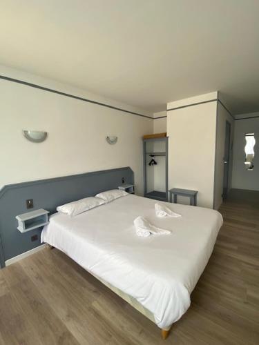 a bedroom with a white bed with two pillows at Hôtel La Tour des Anglais in Mayenne