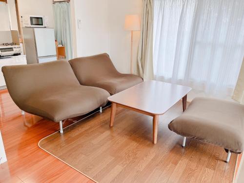 a living room with a couch and two chairs and a table at かぐら庵 in Kitakata