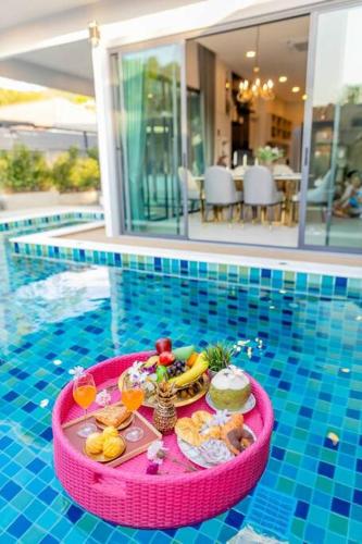 a tray of food and drinks on a table in a swimming pool at Pool Villa No 10 by Duangtham in Ban Khlong Haeng