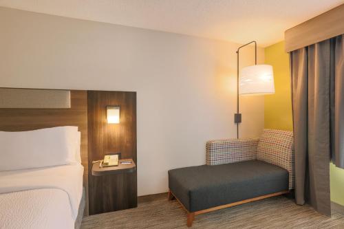 a hotel room with a bed and a chair at Holiday Inn Express Hotel & Suites Wake Forest - Raleigh North by IHG in Wake Forest