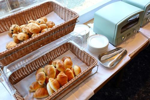 two baskets of pastries on a table next to plates at Hill Hotel Sunpia Iga in Iga