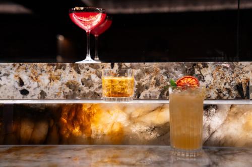 three cocktails sitting on a bar with a wine glass at Marsden Viaduct in Auckland