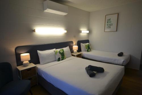 a small room with two beds and two lamps at South Seas Motel in Merimbula