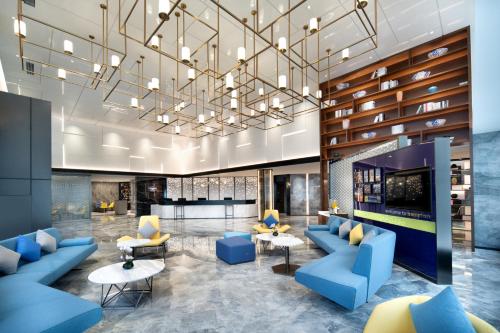 a lobby with blue couches and tables and a chandelier at 东莞大朗希尔顿欢朋酒店 in Huangcaolang