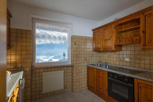 a kitchen with wooden cabinets and a window and a sink at Residence Villa Boschetto in Carano
