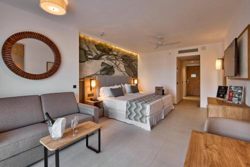 a hotel room with a bed and a couch at Riu Palace Mauritius - All Inclusive - Adults Only in Le Morne
