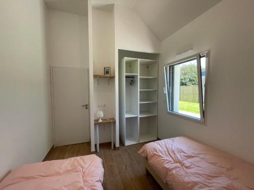 une petite chambre avec deux lits et une fenêtre dans l'établissement Ty Gwag Plain-Pied proche plage de Pors Carn, à Penmarcʼh