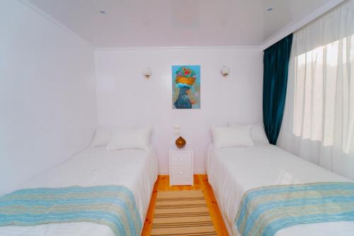 two beds in a room with white walls and windows at Turquoise Dahabiya , 3,4,7 nights sailing between Luxor and Aswan in Luxor