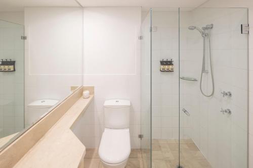 a bathroom with a toilet and a glass shower at Peppers The Hills Lodge in Castle Hill