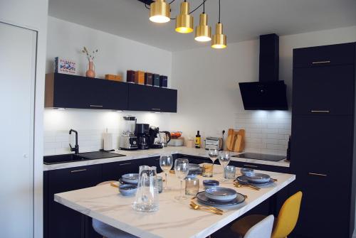 a kitchen with a table with plates and glasses on it at Blue Sand - Appartement cosy-neuf à 500 m du bourg in Saint-Philibert