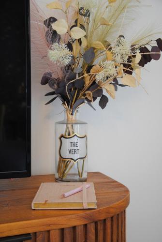 un vase avec des fleurs assis sur une table dans l'établissement Blue Sand - Appartement cosy-neuf à 500 m du bourg, à Saint-Philibert