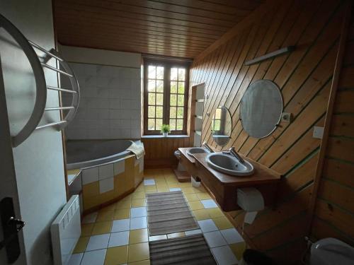 une salle de bain avec un lavabo, une baignoire et un miroir dans l'établissement Maison de bourg, à Carcagny
