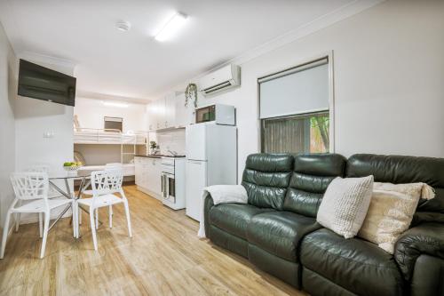 a living room with a black leather couch and a table at Tasman Holiday Parks - Torquay Palms in Hervey Bay
