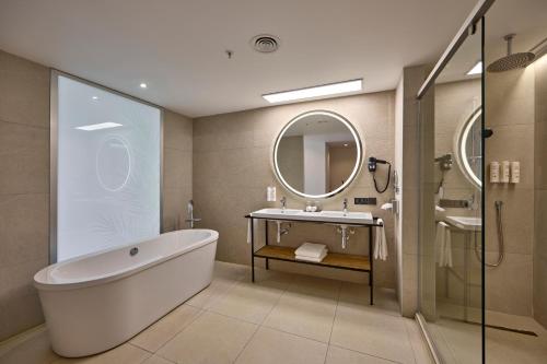 a bathroom with a tub and a sink and a mirror at Riu Palace Mauritius - All Inclusive - Adults Only in Le Morne