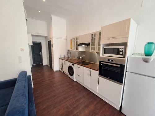 une cuisine avec des armoires blanches et un réfrigérateur blanc dans l'établissement Au Méditerranéen, à Marseille