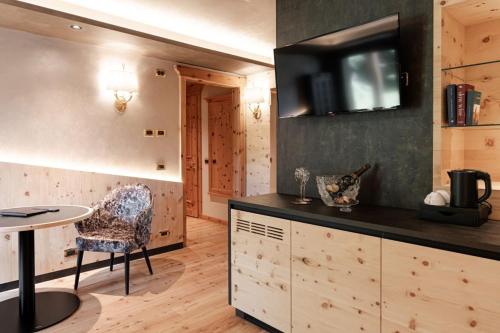 a kitchen with a table and a tv on the wall at Cerana Relax Hotel in Madonna di Campiglio