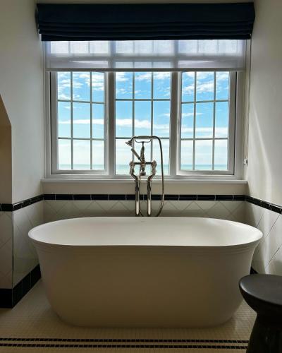 a bath tub in a bathroom with a window at The White Horses by Everly Hotels Collection in Rottingdean