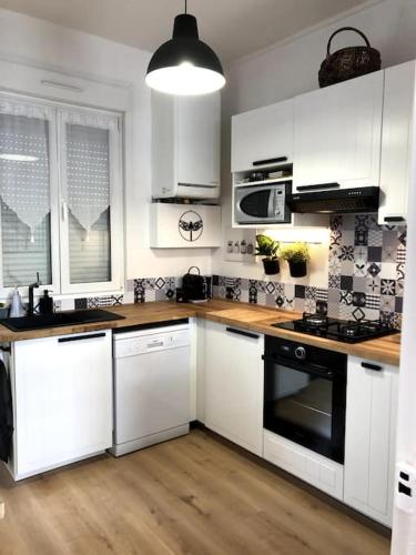 une cuisine avec des armoires blanches et un four à plaques de cuisson dans l'établissement maison de vacances, à Berck-sur-Mer