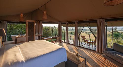 a bedroom in a tent with a bed and a couch at Saruni Eagle View in Naboisho